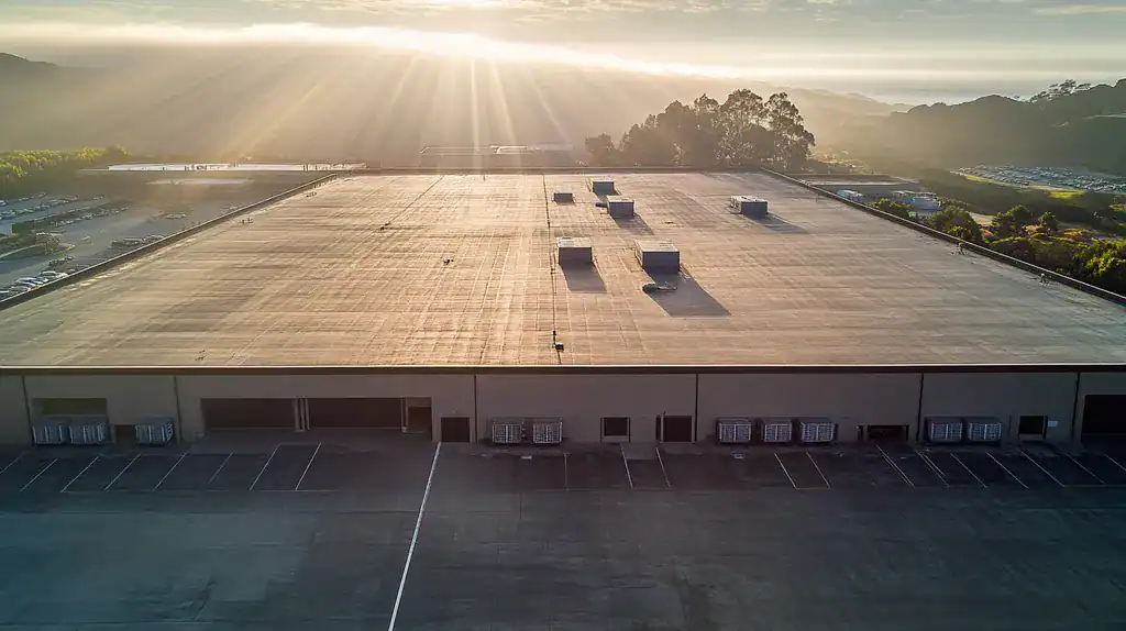 A commercial roof on a distribution center in a location similar to Big Sur with a light beams aesthetic (AI image)