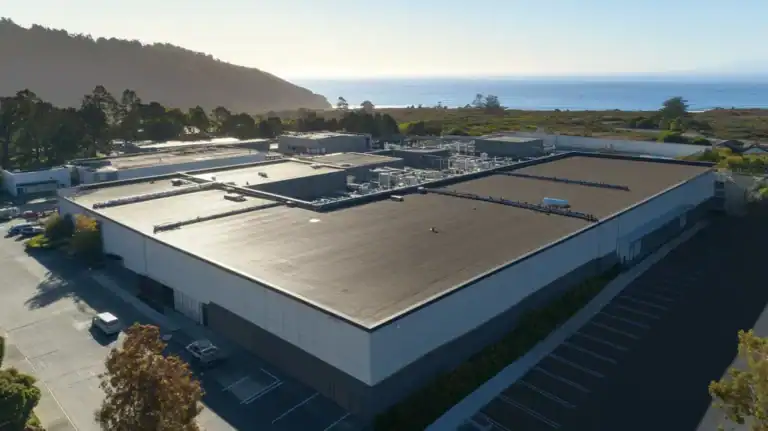 A commercial roof on a manufacturing plant in a location similar to Big Sur with a color highlight aesthetic (AI image)