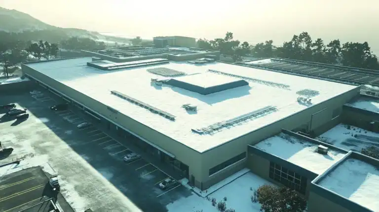 A commercial roof on a manufacturing plant in a location similar to Big Sur with a snowy day aesthetic (AI image)