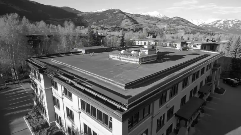 A commercial roof on a mid-rise in a location similar to Aspen with a black and white photography aesthetic (AI image)