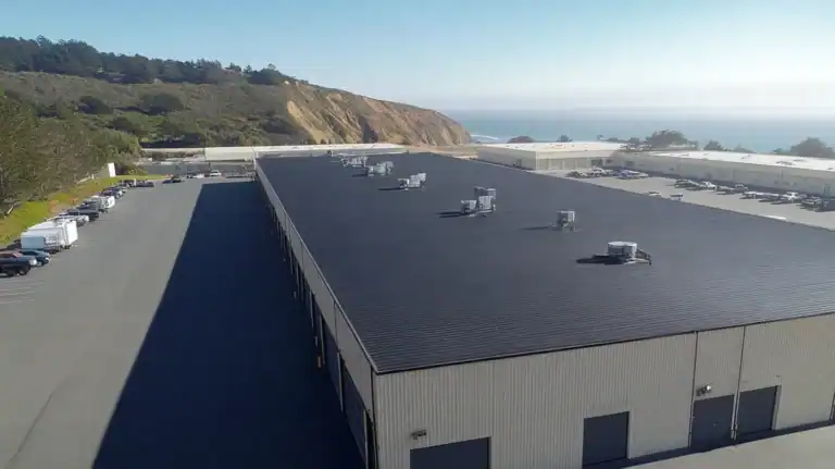 A commercial roof on a warehouse in a location similar to Big Sur with a color highlight aesthetic (AI image)