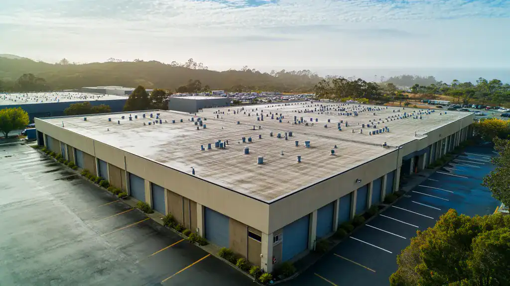 A commercial roof on a warehouse in a location similar to Big Sur with a rainy day aesthetic (AI image)