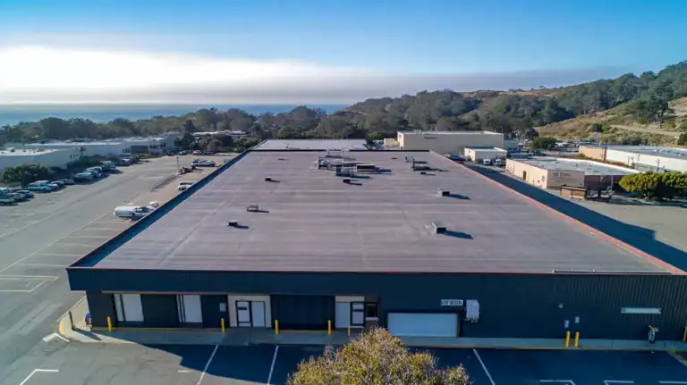 A commercial roof on a warehouse in a location similar to Big Sur with an urban context aesthetic (AI image)