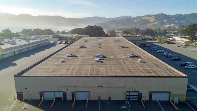A commercial roof on a warehouse in a location similar to Big Sur with an urban context aesthetic (AI image)